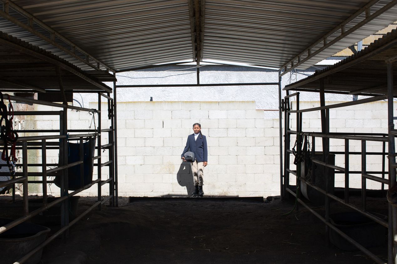 Young female equestrian in a horse stable, Ilona Szwarc, Los Angeles editorial photographer. 