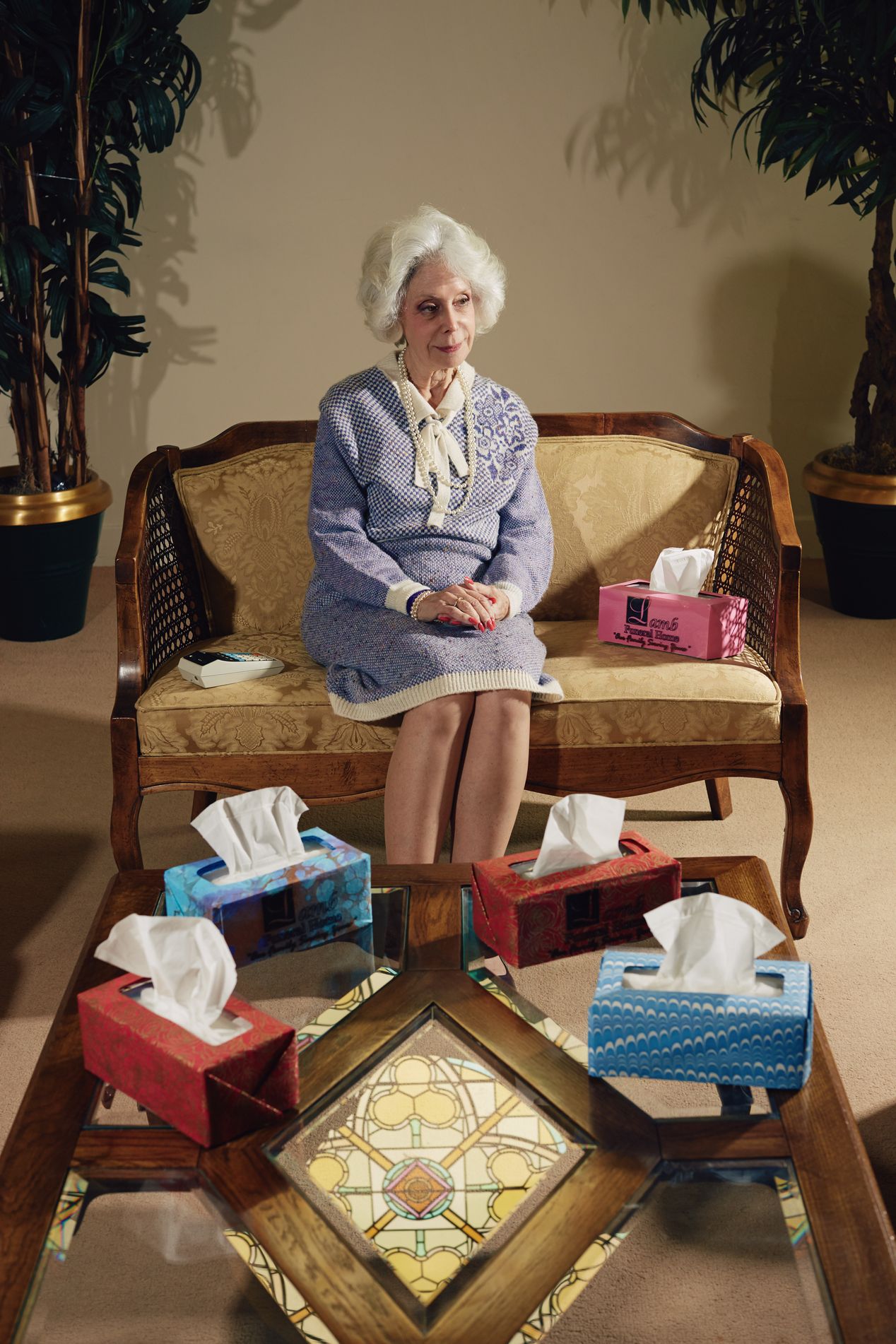 An older female sitting on a couch, surrounded by tissues and tissue boxes, Ilona Szwarc, Los Angeles editorial photographer.