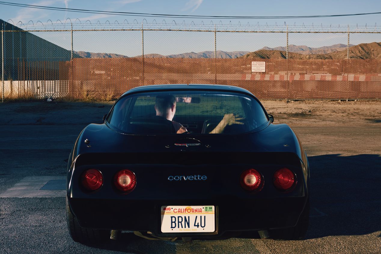 The back of a black Corvette with a man sitting inside it, Ilona Szwarc, Los Angeles editorial photographer.
