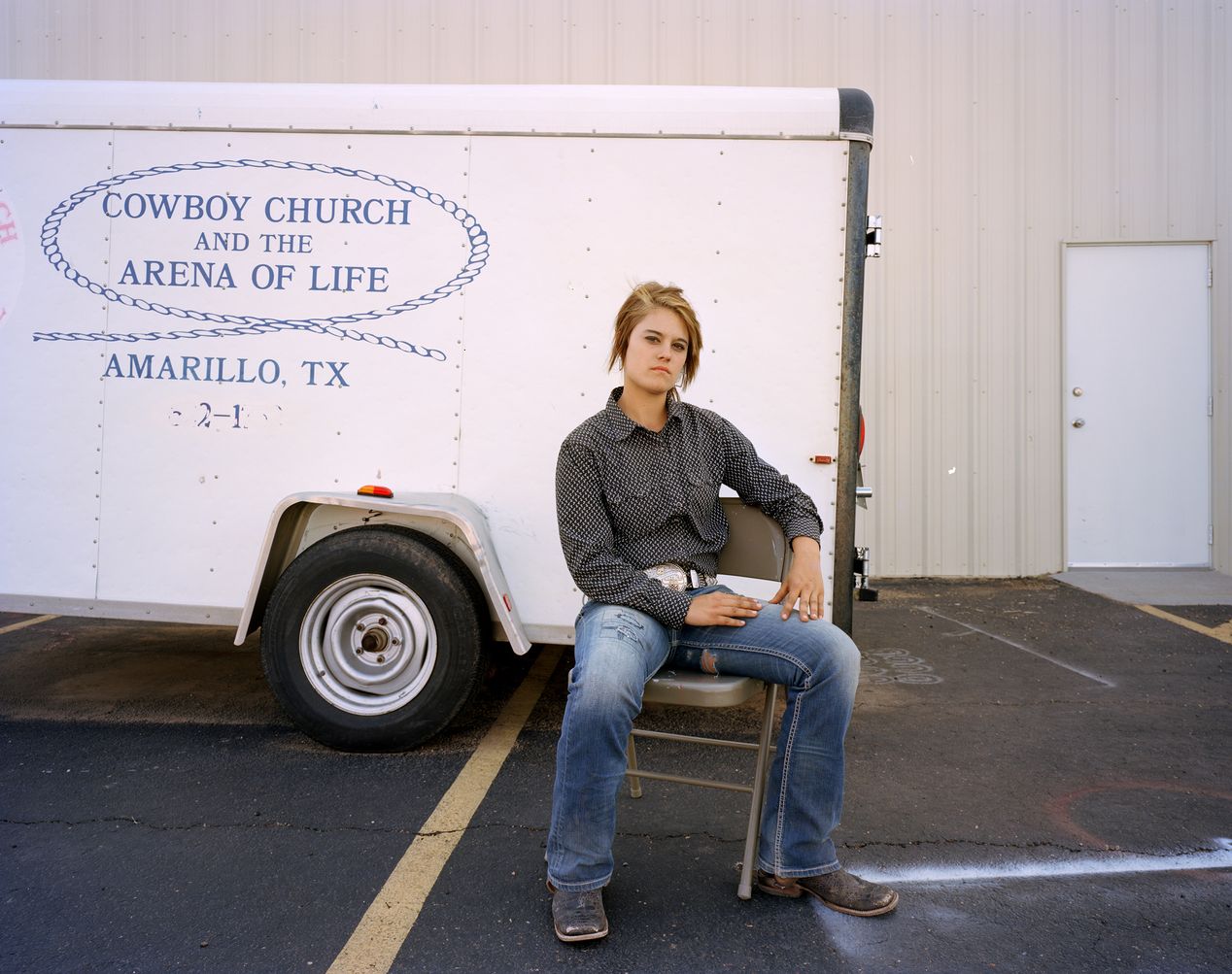 Teenage rodeo girl sitting next to a trailer, environmental portrait photography, Ilona Szwarc, contemporary Los Angeles artist.