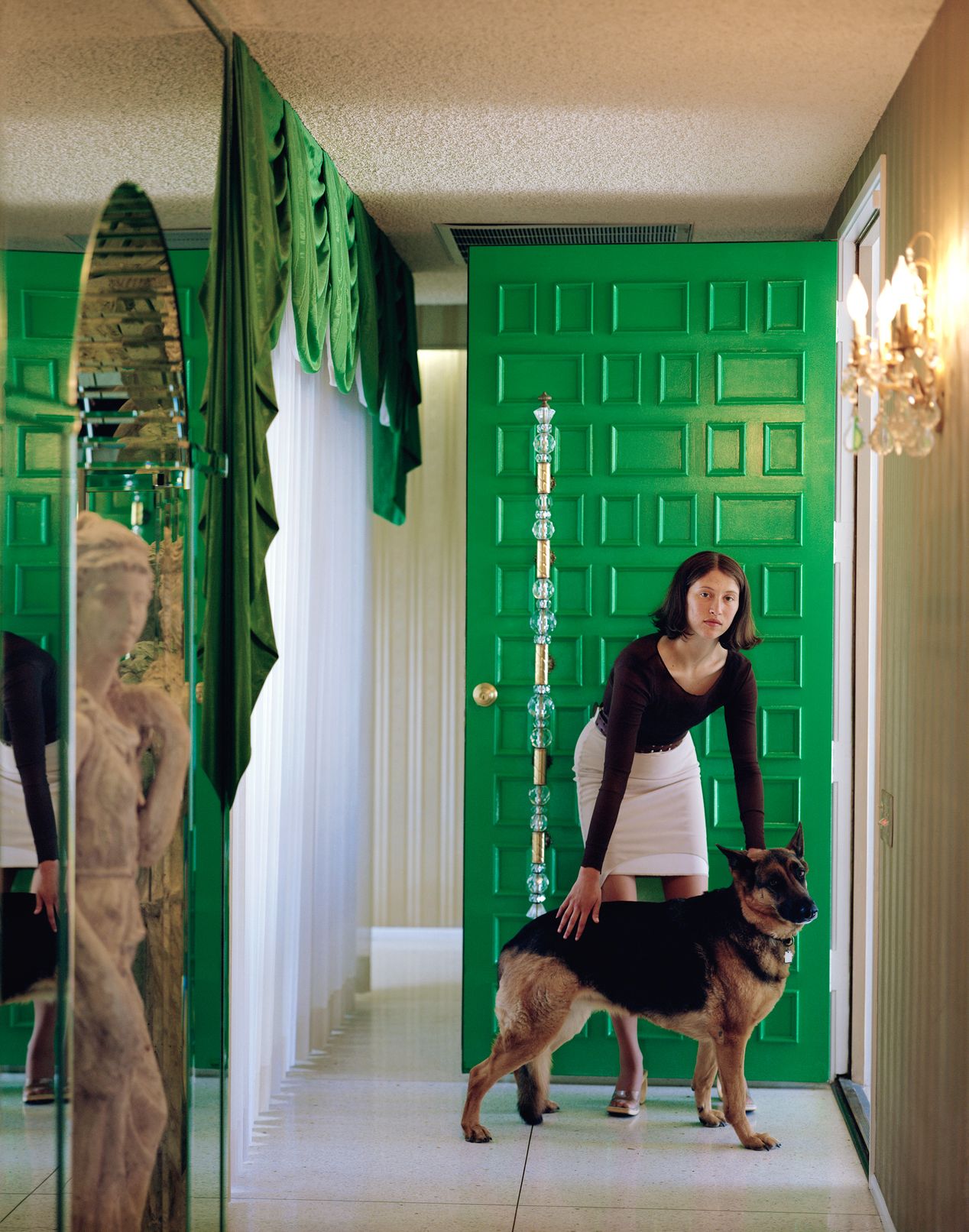 A young woman with her dog against a green front door, art photography, Ilona Szwarc, contemporary Los Angeles artist.